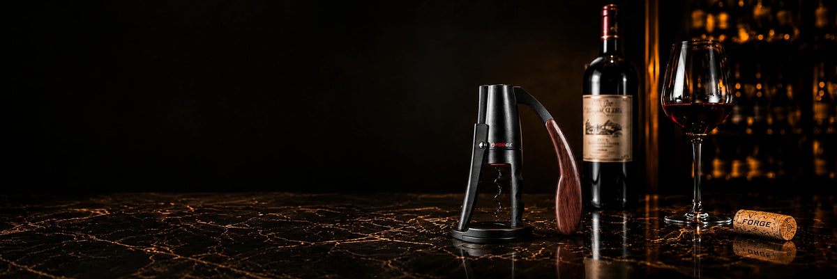 FORGE lever wine opener beside wine and crystal glassware